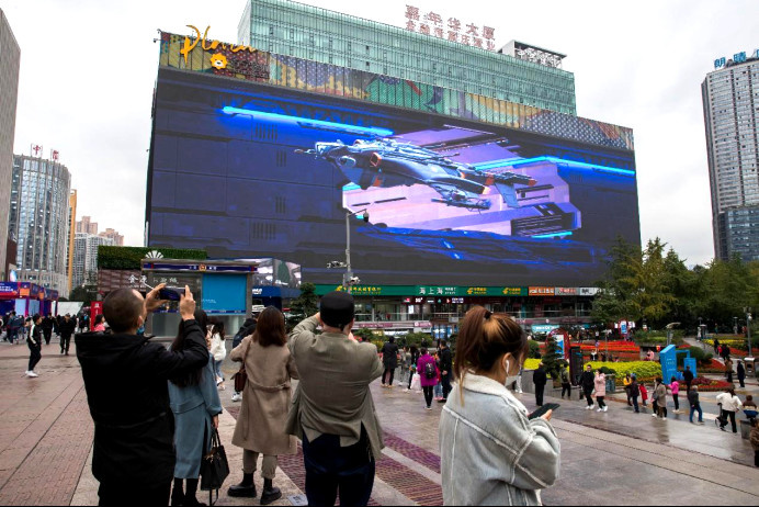 Citizens take photos of a giant naked-eye 3D LED display in Jiangbei district, southwest China's Chongqing municipality. (Photo by Sun Kaifang/People's Daily Online)