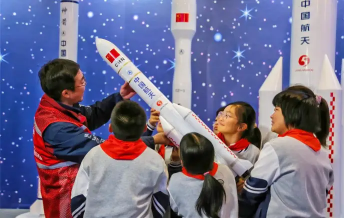 A volunteer (first from the left) shares knowledge of aerospace with local students, holding a model rocket, at a science and technology museum in Hai'an, east China's Jiangsu province, Dec. 8, 2022. (Photo by Zhou Qiang/People's Daily Online)
