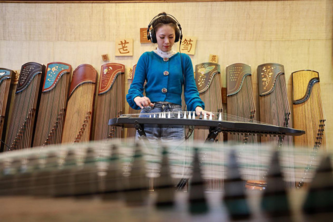 A woman plays electric guzheng in an exhibition hall of musical instruments in Yangzhou, east China's Jiangsu province. (Photo by Feng Jiangjiang/People's Daily Online)