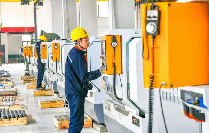 Employees operate production equipment in a workshop of a valve manufacturing company in Bazhong, southwest China's Sichuan province, Feb. 24, 2023. (Photo by Cheng Cong/People's Daily Online)