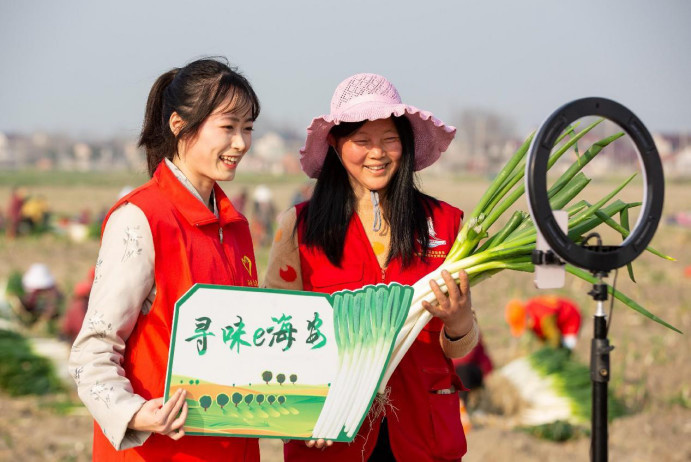 A volunteer and Party head (right) of Hangyao village, Hai'an, east China's Jiangsu province, sell long green onions on a livestream platform, March 7, 2023. (Photo by Zhai Huiyong/People's Daily Online)