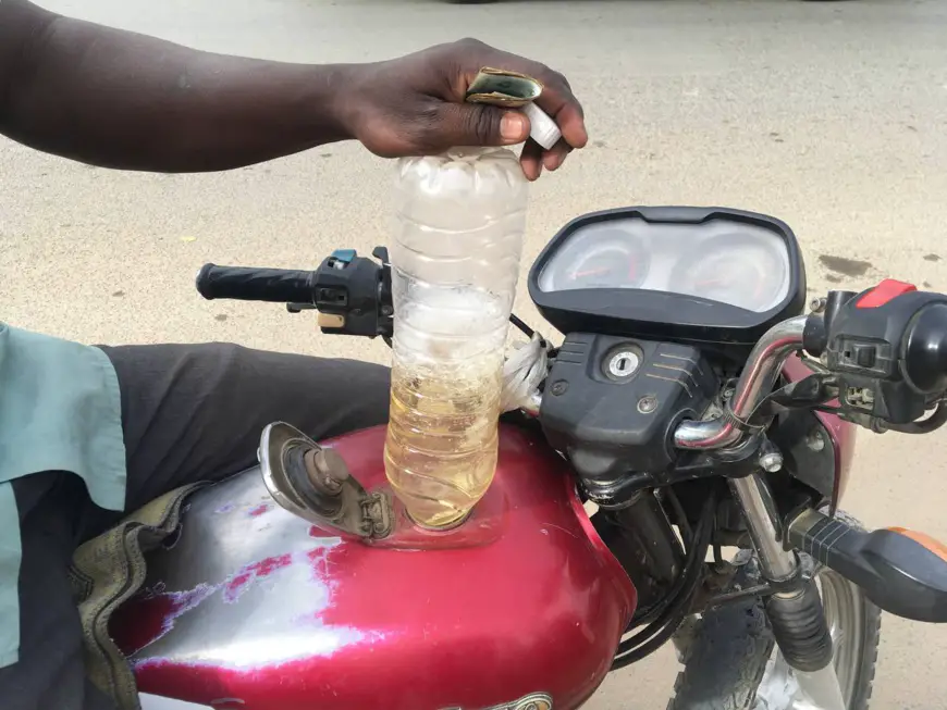 Un motocycliste vide une bouteille d'essence dans le réservoir de sa moto, le 29 avril 2023 à N'Djamena. © Mbaïnaissem Gédéon/Alwihda Info