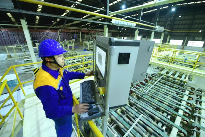 A technician checks the production of a full-automated production line in a factory of a construction materials company in Taicang, east China's Jiangsu province. (Photo by Ji Haixin/People's Daily Online)