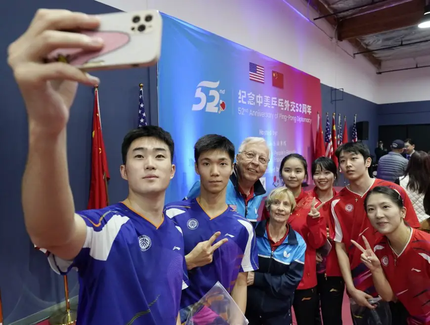 Connie Sweeris (4th L), American table tennis champion who went on the ice-breaking trip to China in 1971, her husband Dell Sweeris (3rd L), and participants from China and the United States take selfies during an event to commemorate the 52nd anniversary of Ping-Pong Diplomacy in Fremont, California, the United States, Dec. 15, 2023. (Photo by Li Jianguo/Xinhua)