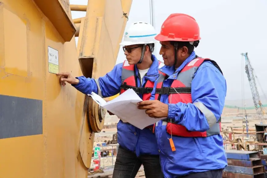 Chinese and Peruvian employees perform equipment maintenance at the construction site of the Chancay Port. (Photo by Qiu Yan)