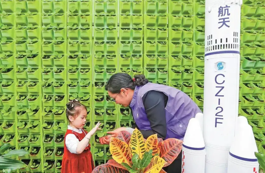 A staff member of a space breeding base presents space plants to a girl in Shexian county, east China's Anhui province. (Photo by Shi Yalei)