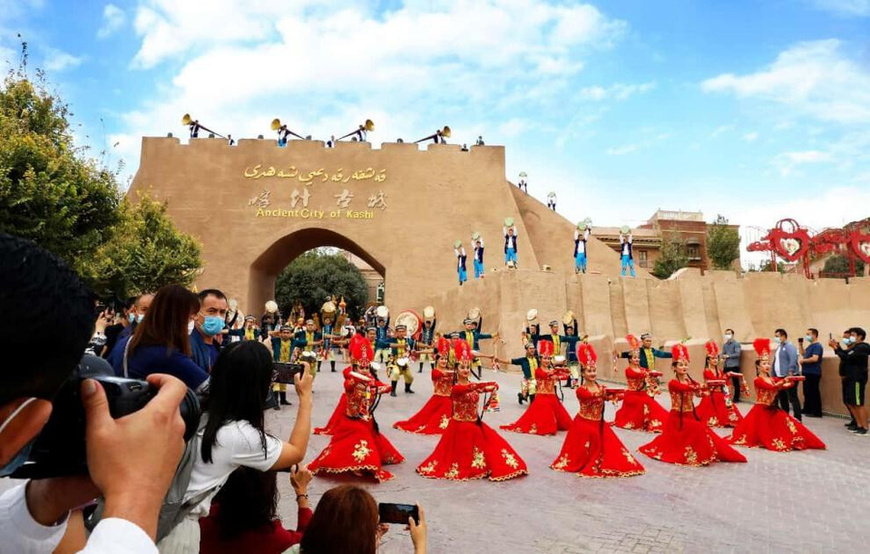 Performers dance outside the ancient city of Kashgar to welcome tourists. (Photo by Wang Zhenqiang)