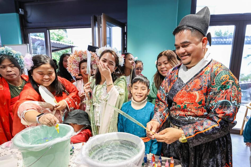 Foreign tourists make lacquer fans in an ancient town in Deqing county, Huzhou, east China's Zhejiang province. (Photo/Yao Haixiang)