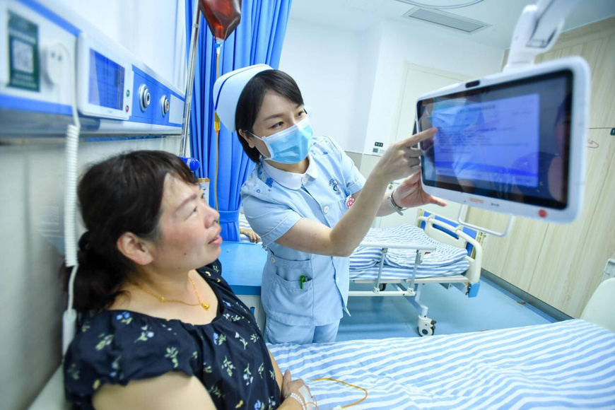 A nurse of Yichun People's Hospital in east China's Jiangxi province reviews a patient's checkup results using a bedside intelligent medical platform. (Photo/Zhou Liang)