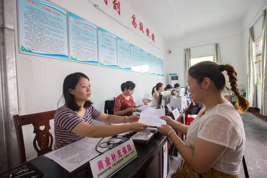 An employee working with the “one-stop” health care settlement center in Wan’an county, Jiangxi Province is handling the settlement procedures for impoverished household, August 7, 2017. (Photo by People’s Daily Online)