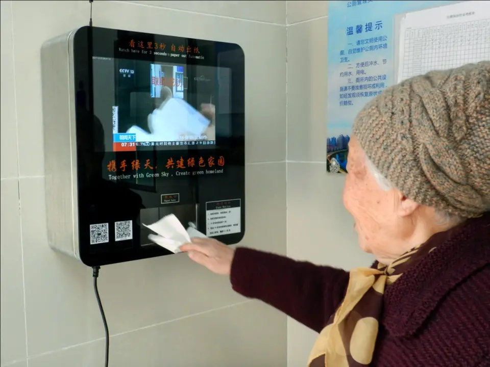 A resident scans her face for toilet paper at a public restroom in Nanjing, capital of east China’s Jiangsu province, December 23, 2017. The newly-established facial recognition machine attracted many curious citizens to experience. (Photo from CFP)
