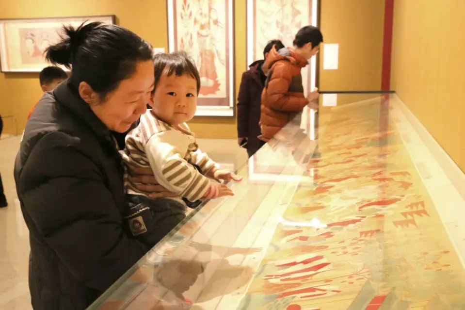 A woman takes her child to the Zhang Daqian Art Exhibition hosted by the National Museum of China, Sichuan Museum, and Rong Bao Zhai folk art gallery. More than 100 masterpieces of Zhang's artworks were exhibited. (Photo by CFP)