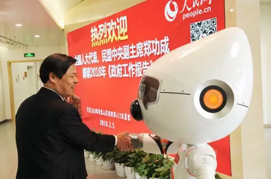 People’s Daily Online’s artificially intelligent robot Wangzai shakes hands with a guest at the two sessions. (Photo by Jiang Jianhua from People’s Daily Online)