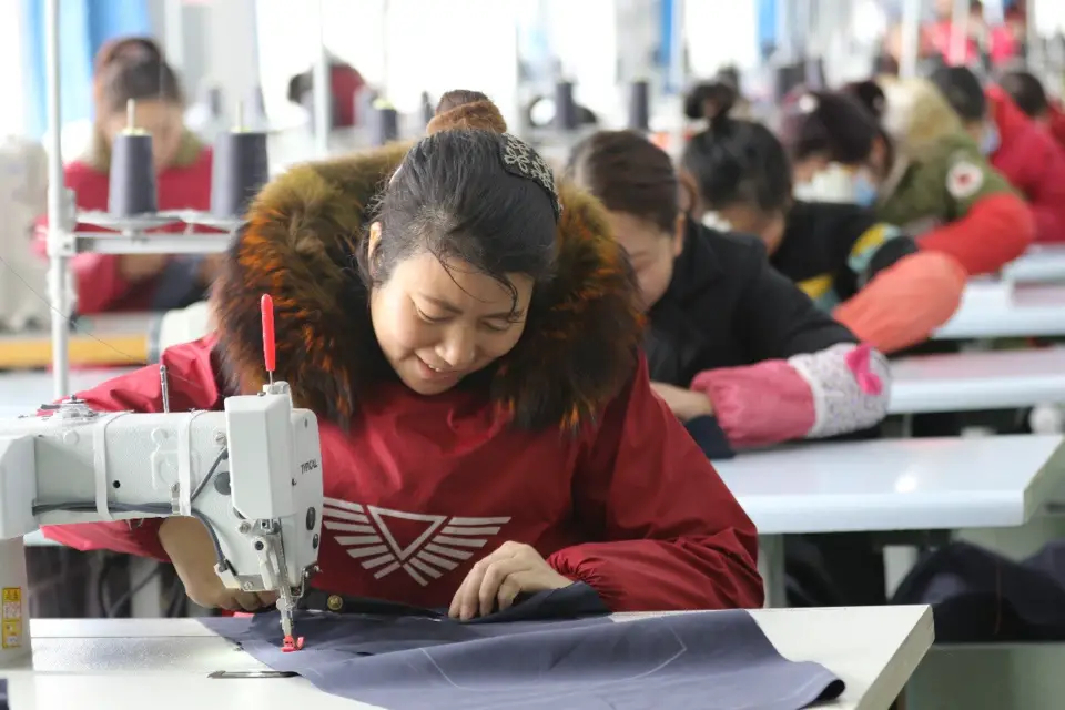 Left-behind women and poor migrant workers make down jackets ordered by customers at a poverty alleviation workshop in an industrial concentration area in Guangshan County, central China’s Henan province, March 9, 2018. (Photo from CFP)