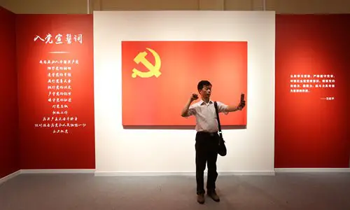 A visitor takes a selfie while pretending to take the oath to join the Party during an exhibition marking the 95th founding anniversary of the Party in Shanghai, July 26, 2016. Photo: VCG