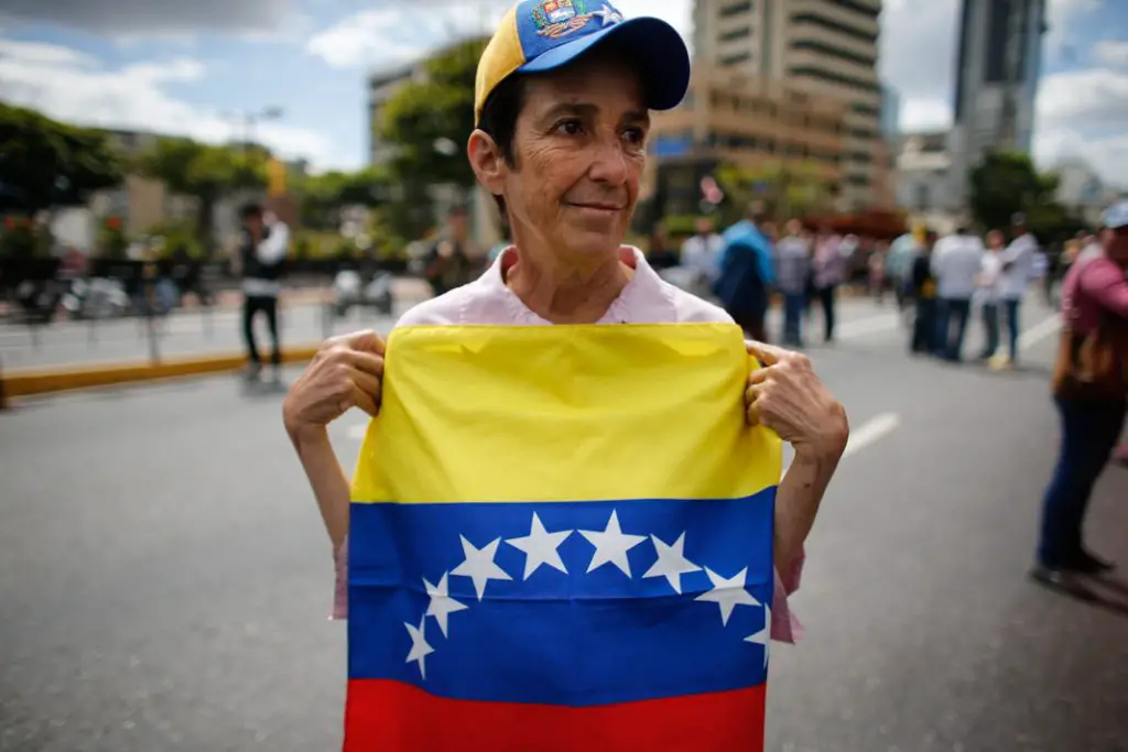 Une femme qui soutient Juan Guaido tient le drapeau national du Venezuela (© Ariana Cubillos/AP Images)