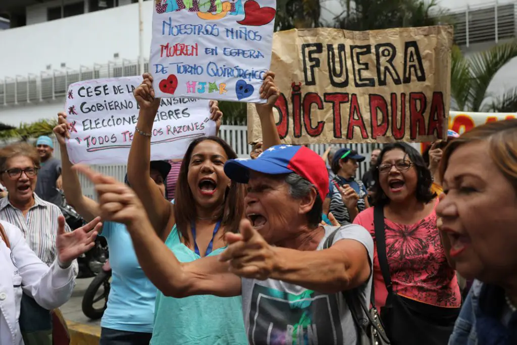 Des partisans de la démocratie brandissent des pancartes réclamant la fin du régime dictatorial de Maduro. (© Rodrigo Abd/AP Images)