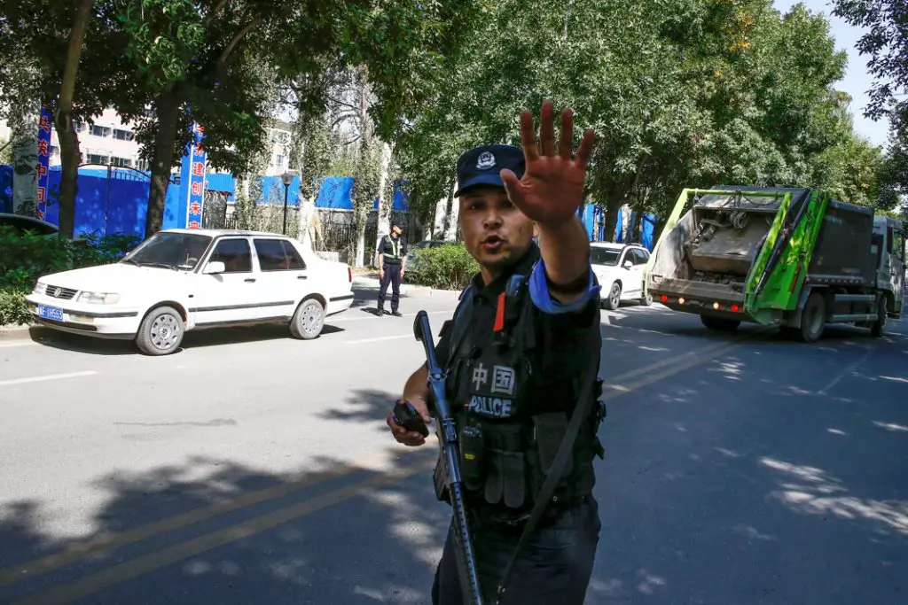 Un policier chinois ordonne à des reporters de ne pas avancer, à proximité d’un centre de détention au Xinjiang. (© Thomas Peter/Reuters)