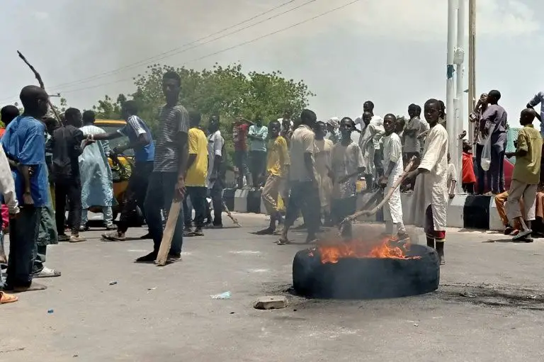Des manifestants bloquent une route principale dans la ville nigériane de Maiduguri, au nord du pays, demandant aux autorités d'interdire une milice locale anti-Boko Haram qui, selon eux, les maltraite (AFP Photo/Audu MARTE)