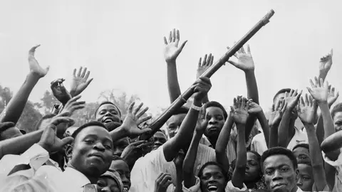 01 Jul 1960, Leopoldville, Congo --- 7/1/1960-Leopoldville, Congo-A group of Congolese wave guns, whoop and shout for joy during the Independence celebrations. --- Image by © Bettmann/CORBIS © Bettmann/CORBIS