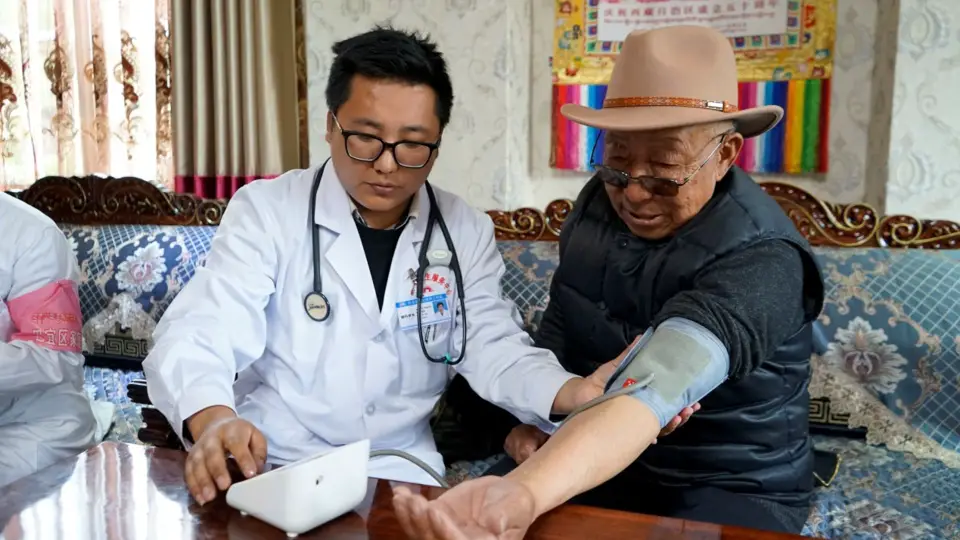 A doctor on a house call checks blood pressure and glucose for a patient in a village in Nyingchi, Tibet Autonomous Region. (By Shen Shaotie, People’s Daily)