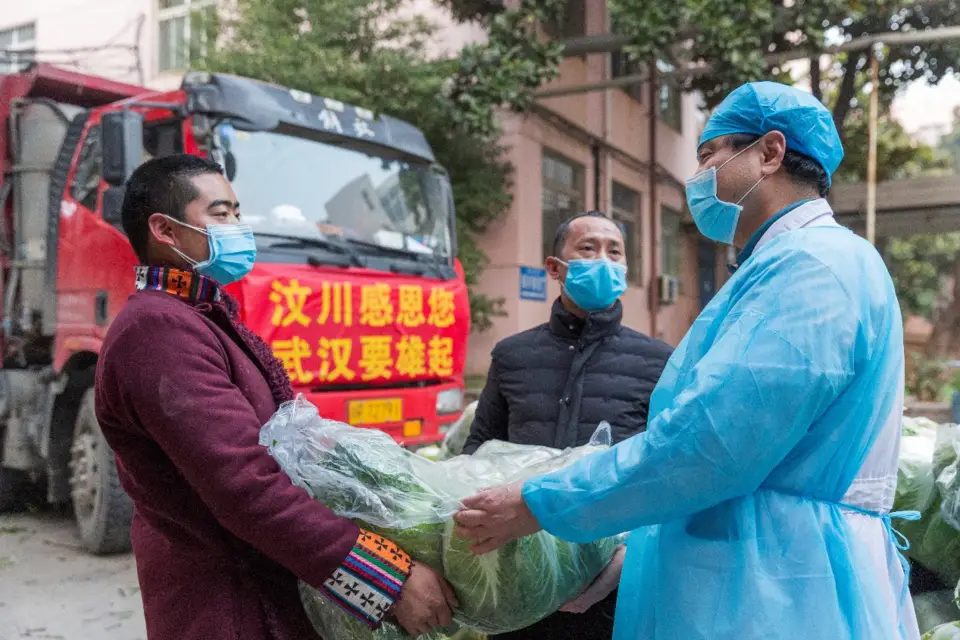 Zhao Yong, Chief of Longzhu village, Wenchuan county of Sichuan province and his fellow villagers deliver vegetables to a medical staff in Wuhan, Feb. 5. The man, together with 12 of his fellow villagers, have donated vegetables to 12 major hospitals in the city. (Photo by Zhang Wujun/People’s Daily)