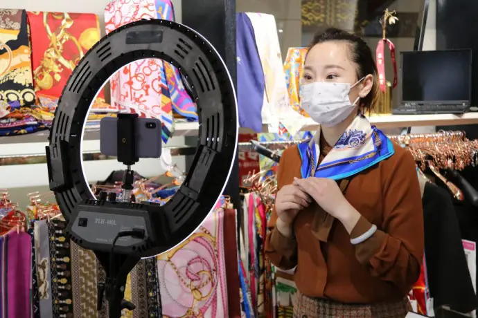 A merchant hosts a livestreaming show to sell her products on Xiushui Street, a shopping center in Chaoyang district, Beijing, March 3, 2020. The shopping center reopened to business on the same day. Liu Jing/People’s Daily Online