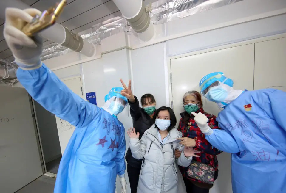 Recovered patients pose for a picture with medical workers before leaving the Huoshenshan Hospital, March 14. Photo by Liu Yibo, People’s Daily Online
