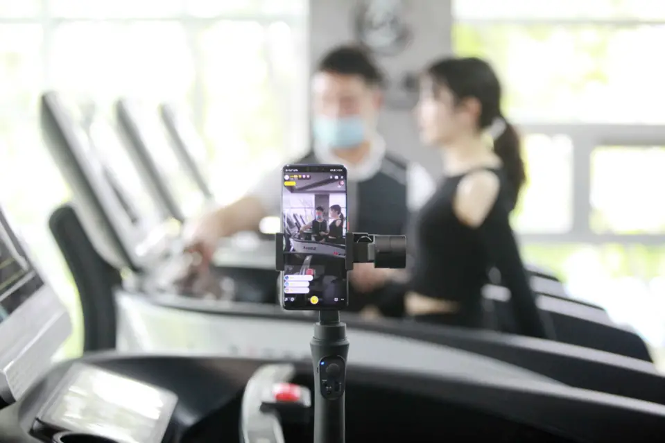A fitness trainer and a trainee livestream a fitness course at a gym in Yangzhou, East China’s Jiangsu Province, April 23. (Photo by Meng Delong/People’s Daily Online)