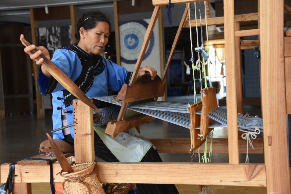 Photo shows a senior woman of the Buyi ethnic group weaves cloth with a loom. Photo by Su Bin, People’s Daily