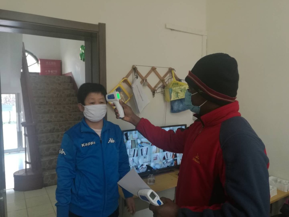 Wen He takes body temperature of a staff member. (Photo/ Wen He)