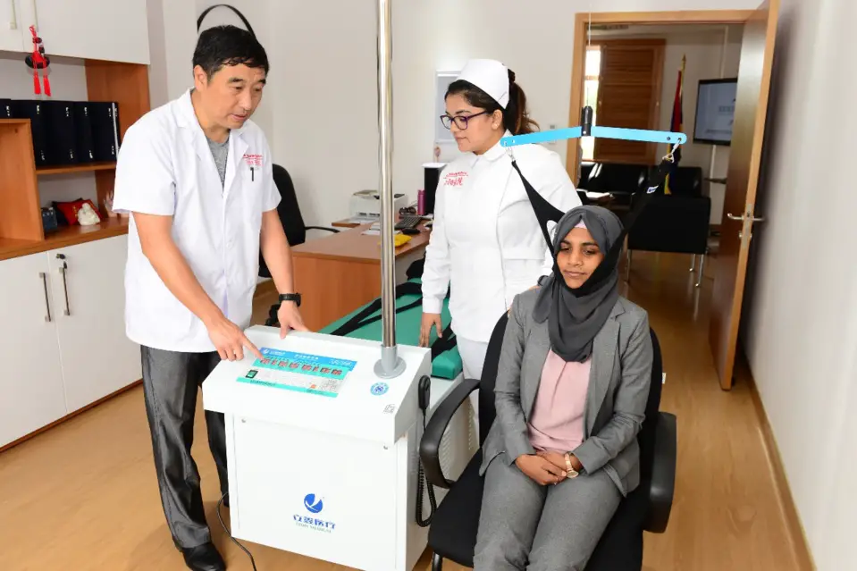 Photo shows Hu Binglin treats a patient who suffers from cervical spondylosis. (Photo courtesy of China-Mauritius Center for Traditional Chinese Medicine)