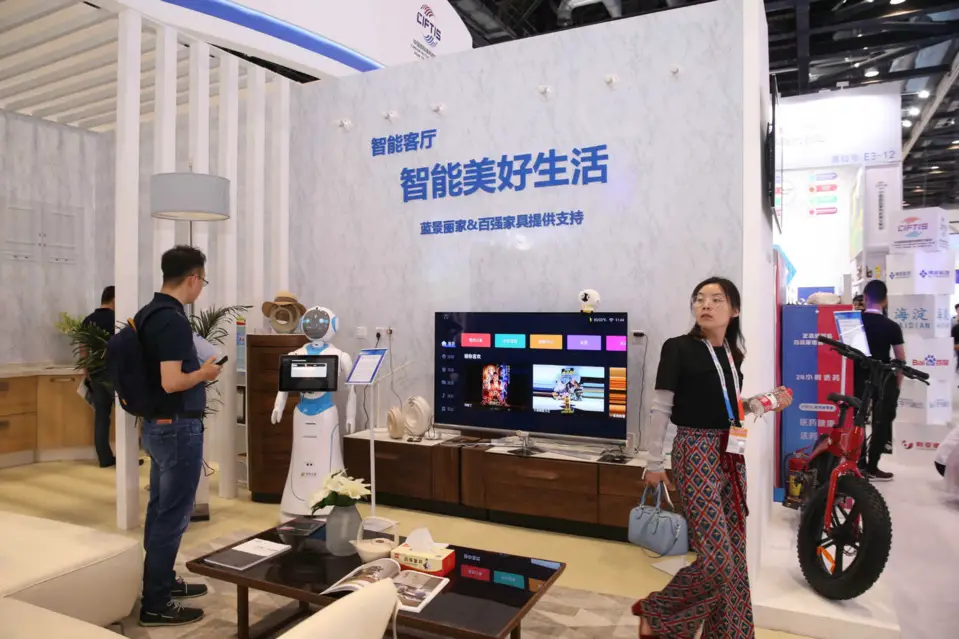 Photo taken on May 29, 2019 shows visitors at a smart living room prototype during the 2019 China International Fair for Trade in Services. (Photo by Chen Xiaogen/People's Daily Online)