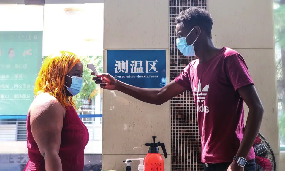Barry (right), a college student at Central China Normal University from Gambia, checks a female student's body temperature on August 28, serving as an anti-epidemic volunteer. Photo: Courtesy of CCNU