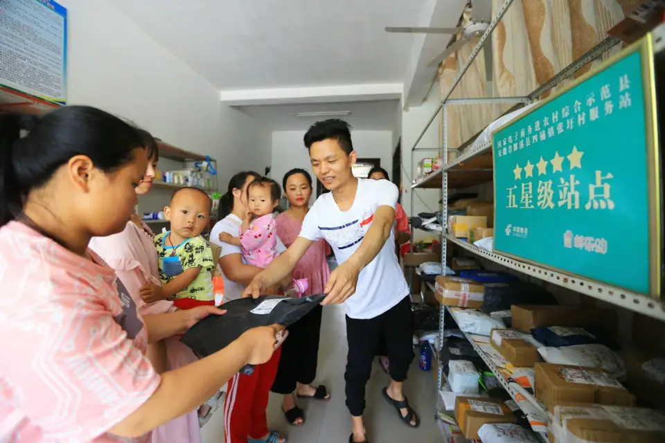 Xin Qingjian (R1), who runs an e-commerce service center in Zhangwei village, Sipu township, Suixi county, Huaibei, east China's Anhui province, hands over a parcel to a villager, June 8. Photo by Wan Shanchao/People's Daily Online