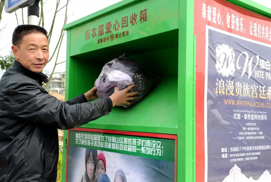 A citizen of Yiwu city put a bag of his own old clothes in the old clothes recycling bin on the street. Photo by Zhang Jiancheng, People’s Daily Online.