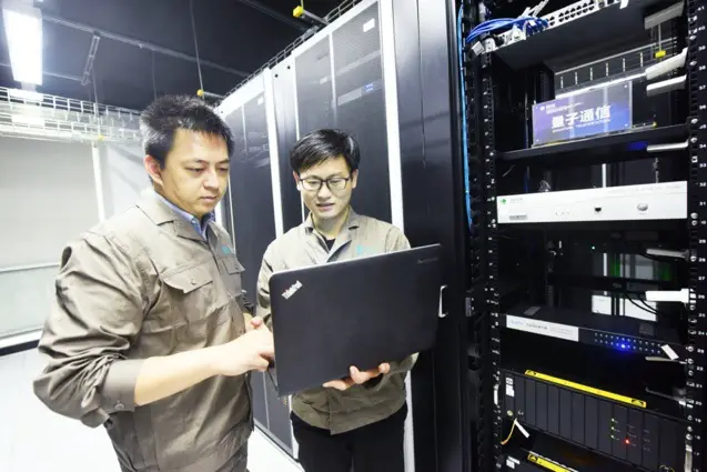 Staff members of the information communication branch of Hangzhou power supply company under China’s State Grid Corporation examine quantum communication device in a communication machine room, Nov. 2. (Photo by Long Wei/People’s Daily Online)