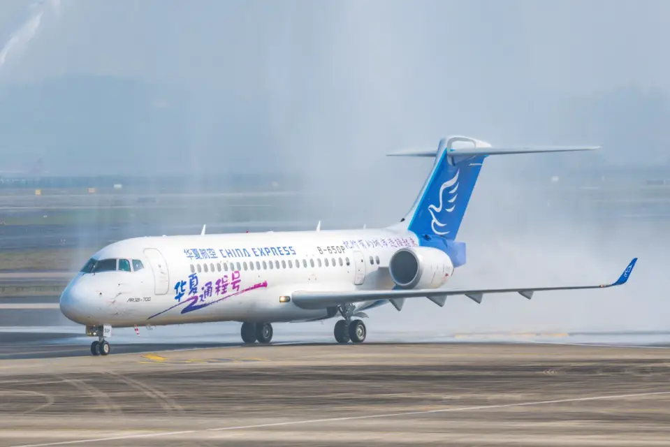 The first ARJ21 aircraft delivered by the Commercial Aircraft Corporation of China, Ltd. to China Express Airlines gets a water cannon salute at the Chongqing Jiangbei International Airport, southwest China's Chongqing municipality, Nov. 10. (Photo by Zou Le/People's Daily Online)