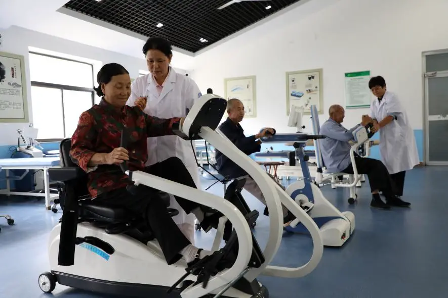 Medical stuffs guide seniors to rehabilitate on professional equipment at a care center in Boxing county, east China's Shandong province, Sept. 3, 2020. (Photo by Chen Bin/People's Daily Online)