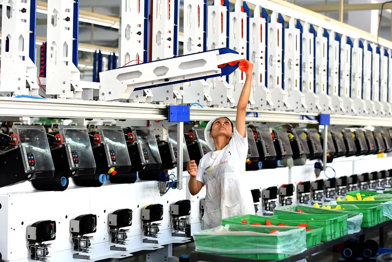 An employee puts a flat-ended tube into an automatic winding machine at a textile factory in Wuyi county, east China's Zhejiang province, Sept. 3, 2020. (Photo by Zhu Hui/People's Daily Online)