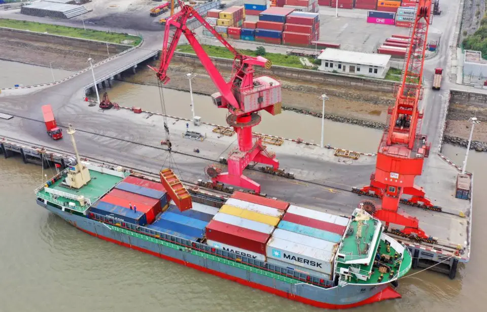 Photo taken on July 12, 2020, shows people loading a cargo vessel with foreign-trade containers at a port in Wenling city, east China’s Zhejiang province. (Photo by Liu Zhenqing/People’s Daily Online)