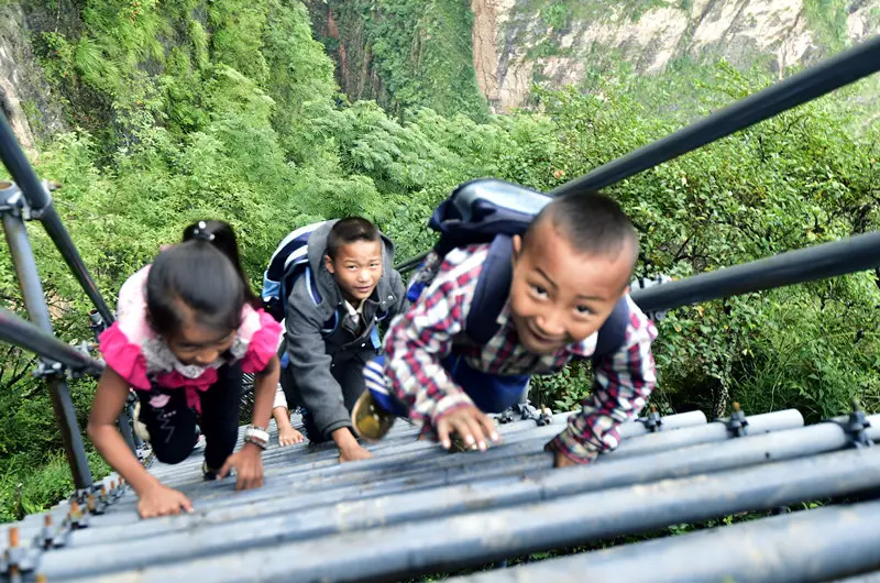 Children climb up a newly-built steel ladder along the cliff in Atulie’er village, Zhaojue county, Liangshan Yi autonomous prefecture, southwest China's Sichuan province, November 2017. (Photo by Rao Guojun/People's Daily)