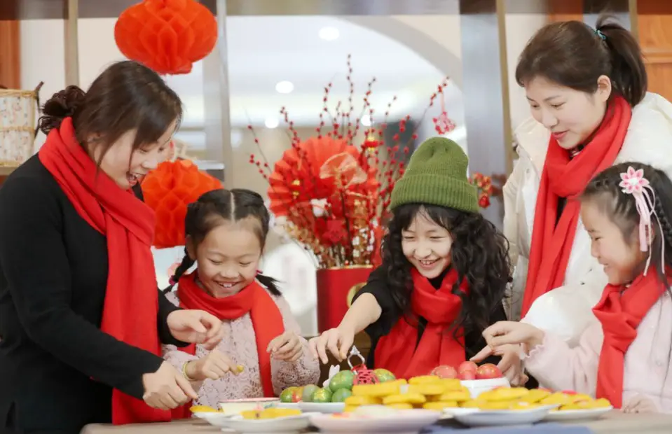 Teachers help children of migrant workers who decide to stay where they work for the upcoming Spring Festival make traditional pastries to celebrate the holiday in Leidian township, Huzhou, east China’s Zhejiang province, Jan. 31, 2021. (Photo by Xie Shangguo/People's Daily Online)