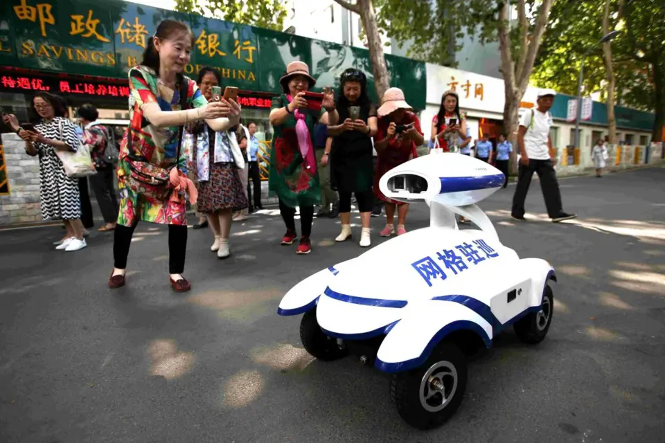 A smart robot patrolling a residential complex in Jinan, capital of east China’s Shandong province, attracts the attention of citizens, July 21, 2020. The smart patrol robot can identify hazardous conditions and illegal activities like noise, fire hazard, and illegal parking and send messages to the police of the local community. (Photo by Hao Xincheng/People’s Daily Online)