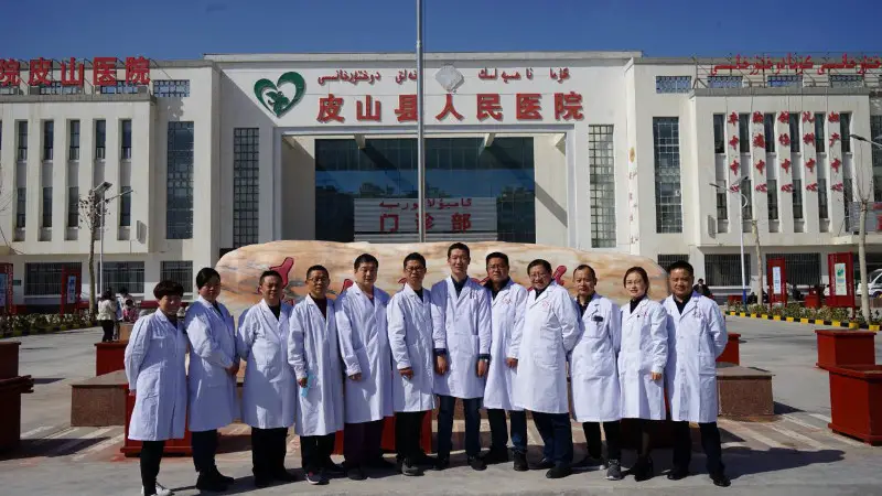 Twelve medical workers sent by east China's Anhui province to assist the People's Hospital of Pishan County in Pishan county, Hotan prefecture of northwest China's Xinjiang Uygur autonomous region, pose for a group photo in front of the People's Hospital of Pishan County, March 4, 2021. (Photo/Official website of the Health Commission of Anhui Province)