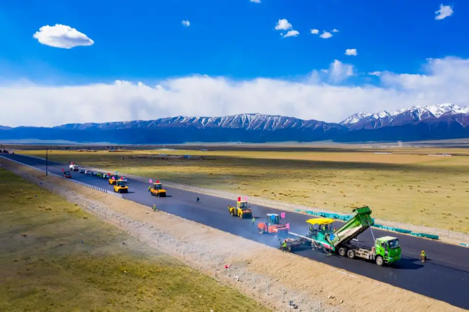 Asphalt is being laid at the junction of an extended section of the G575 expressway and the Beijing-Urumqi Expressway, May 20, 2021. (Photo by Polat Niyaz/People's Daily Online)