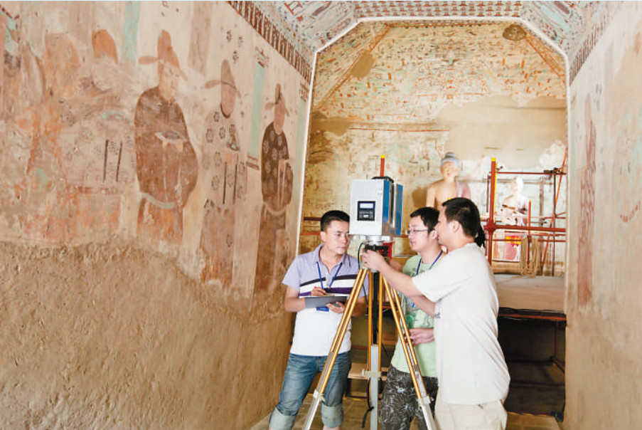 Huang Xianfeng (right) and Zhang Fan (middle), both researchers devoted to the preservation of Mogao Grottoes in Dunhuang, northwest China’s Gansu province, scan murals in a cave with a staff member of Dunhuang Academy China. (File photo)