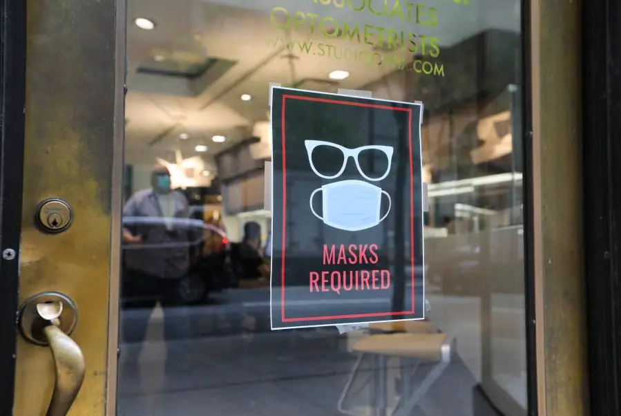 A sign is seen at the entrance to an optical shop in New York City, the United States, Aug. 2, 2021. (Xinhua/Wang Ying)