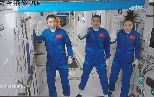 Screen image captured at Beijing Aerospace Control Center on Oct. 16 shows three Chinese astronauts of the Shenzhou-13 crewed space mission—Zhai Zhigang (middle), Wang Yaping (right), and Ye Guangfu (left), waving after entering the Tianhe core module of China’s Tiangong space station. (Photo by Tian Dingyu/Xinhua)