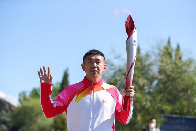 The torch for the Beijing 2022 Winter Games is passed to former Chinese short track speed skater Li Jiajun, the second torchbearer, Oct. 18. (Photo by Zheng Huansong/Xinhua)